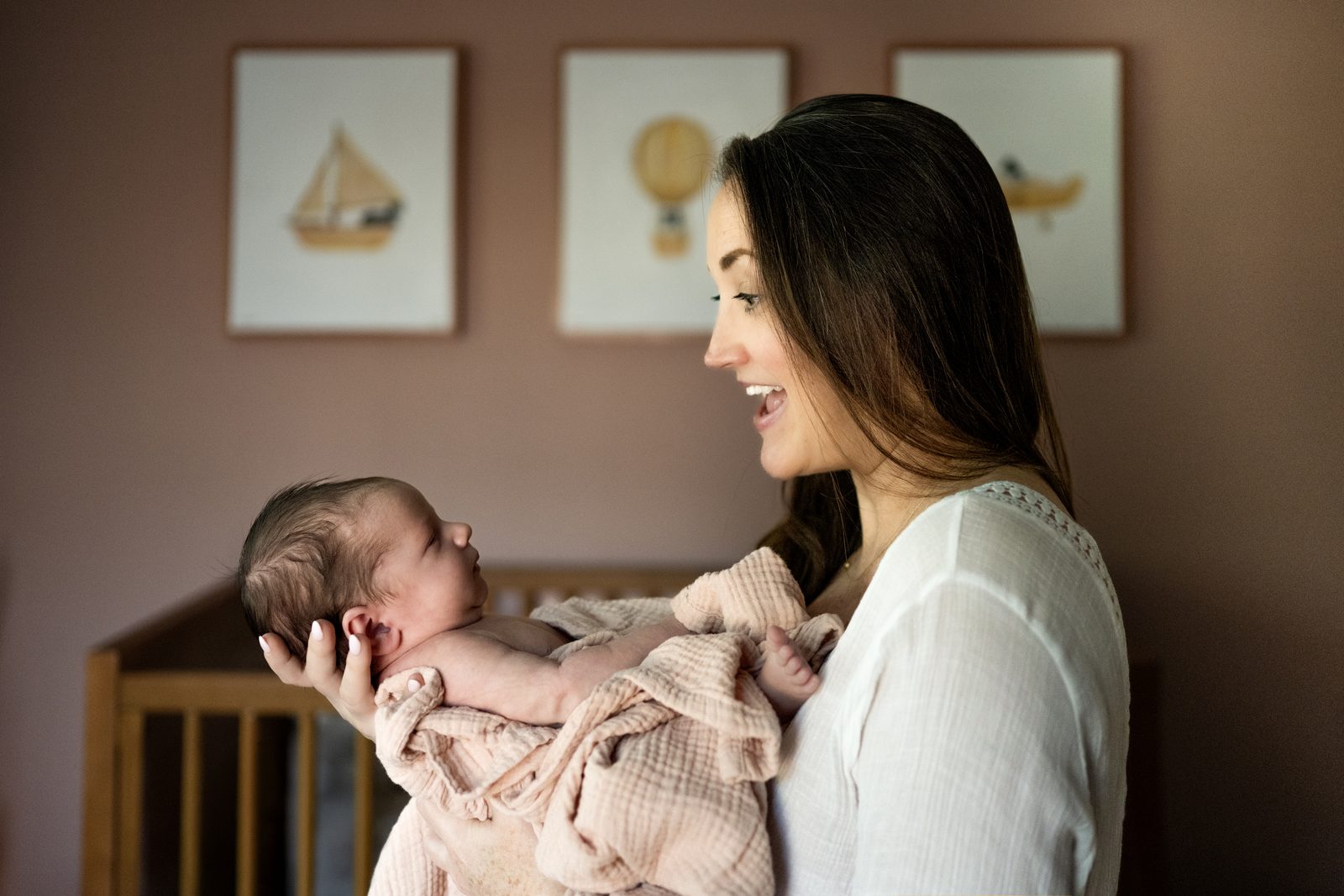 A mother cradling her newborn in a soft, sunlit nursery